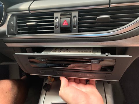 MI-Haupteinheit im Audi A6/A7 wird vorsichtig nach vorne herausgezogen, um die rückseitigen Anschlüsse freizulegen